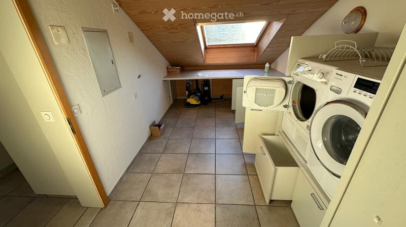 Compact bathroom with a washing machine, dishwasher, and built-in cabinets. Features a skylight window and tiled flooring.