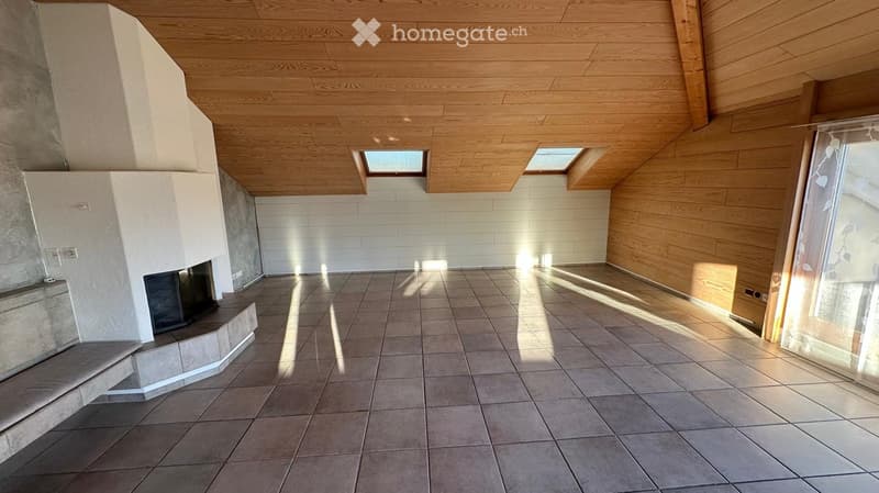 Empty room with tiled floor, wooden ceiling, and built-in fireplace. Natural light from skylights and large window.