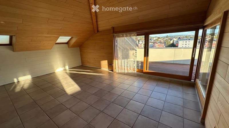 Empty room with wooden ceiling, tiled floor, large windows, and skylights, offering a view of the city.