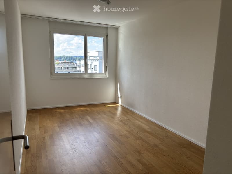 Empty room with wooden flooring and large window offering a view of the outside. No furniture or equipment present.