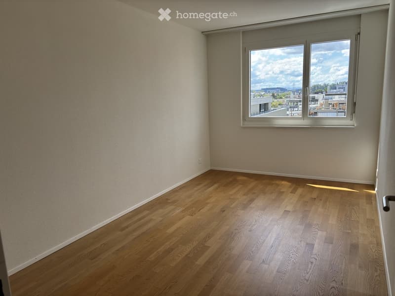 Empty room with wooden flooring and large window offering a view of the cityscape.