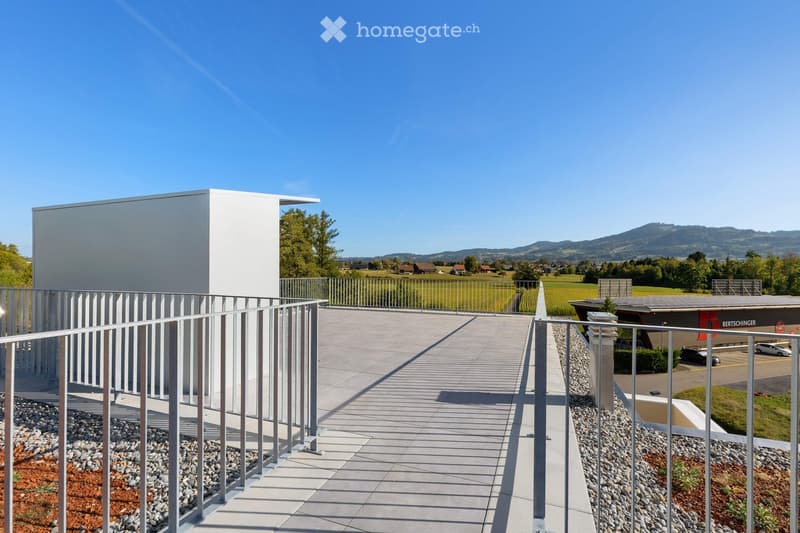 Modern balcony with metal railing, tiled floor, and scenic countryside view in the background.
