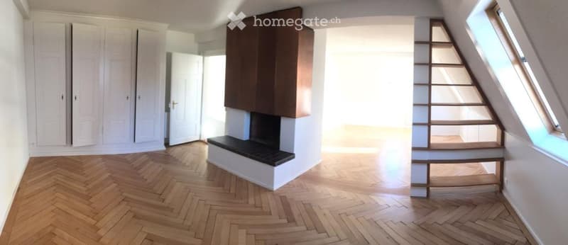 Empty room with wooden herringbone flooring, white walls, built-in cabinetry, and a staircase leading upwards.