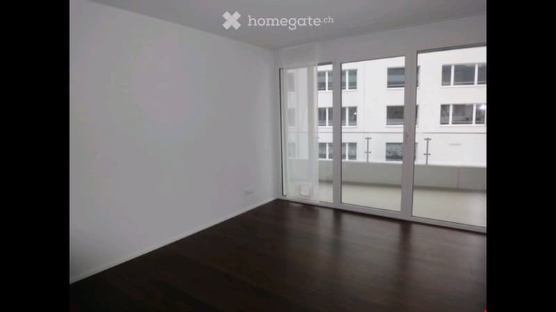 Empty room with wooden flooring and large glass sliding doors leading to a balcony.