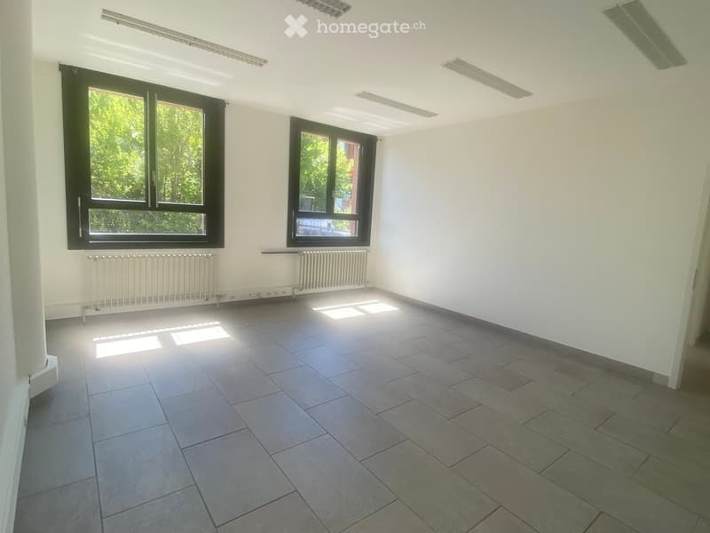 Empty room with tiled floor, white walls, large windows, and radiators.