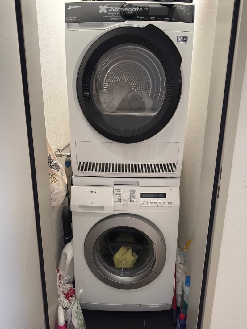 A compact bathroom with a stacked washing machine and dryer unit, both featuring control panels and visible laundry inside.