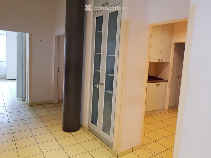 Empty room with yellow tiles, white walls, glass cabinet, and a pillar.