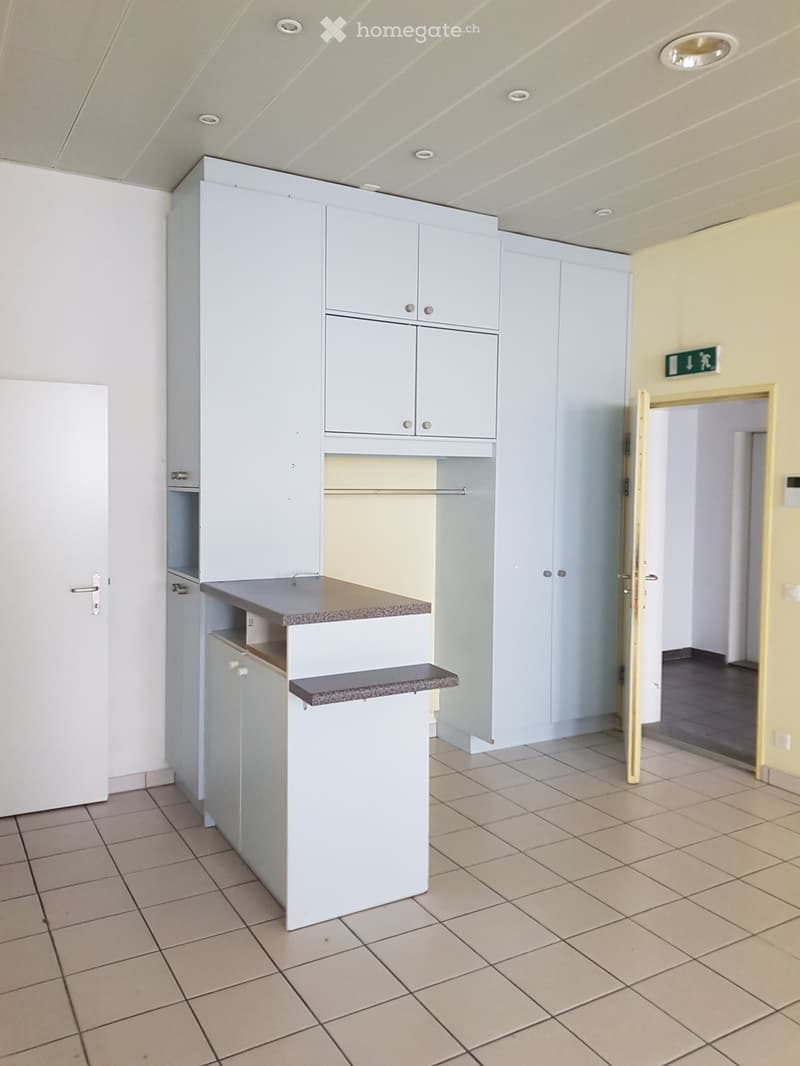 empty room with white cabinets, tiled floor, open door