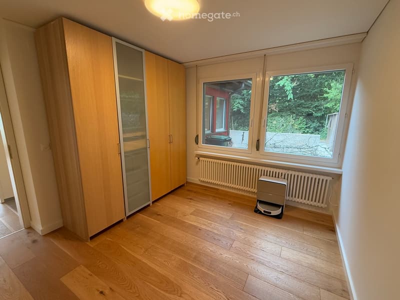 Empty room with wooden flooring, large windows, and a built-in wardrobe. No furniture or equipment present.