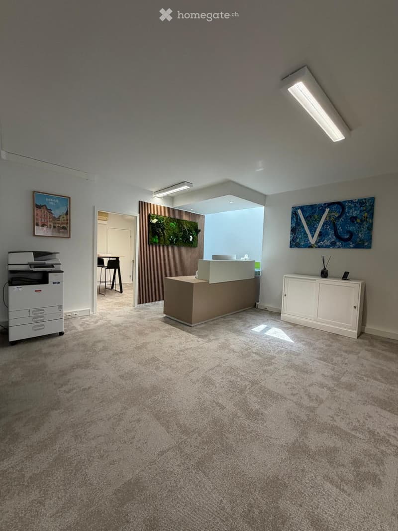 Modern reception area with a reception desk, printer, white cabinet, and artwork on the walls.