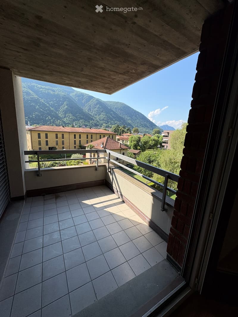 Balcony with tiled floor, metal railing, and scenic mountain view in the background.