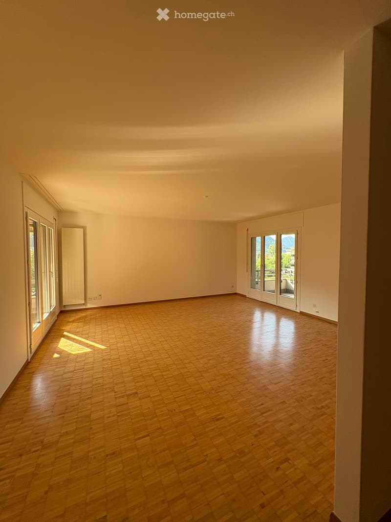 Empty room with wooden flooring, large windows, and natural light. No furniture or equipment present.