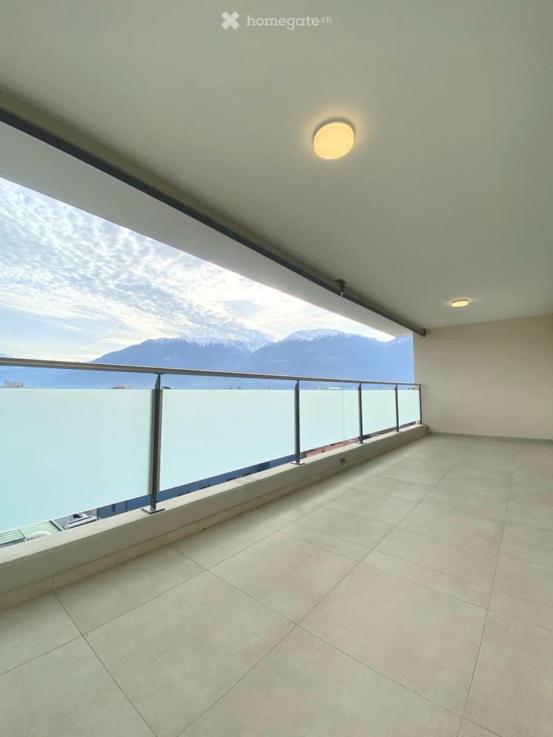Balcony with tiled floor, glass railing, and scenic mountain view.