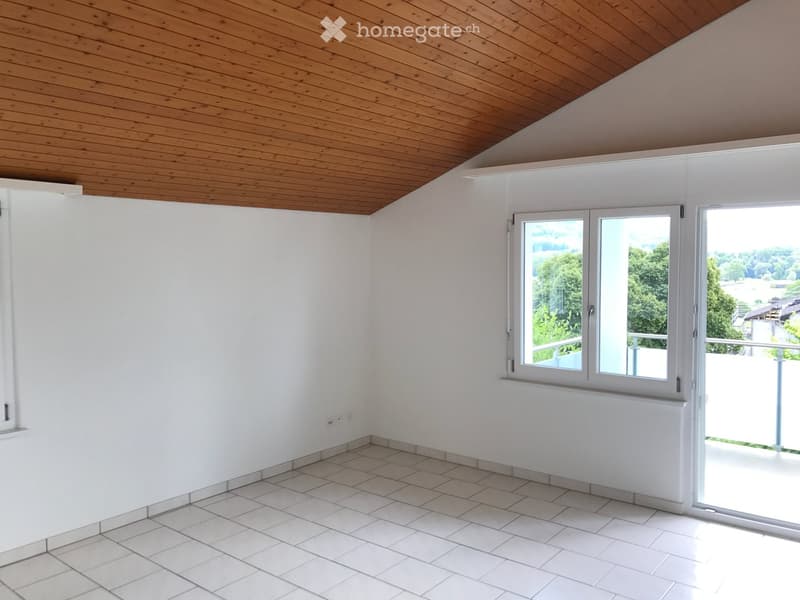 Empty room with white walls, tiled floor, large window, and wooden ceiling.