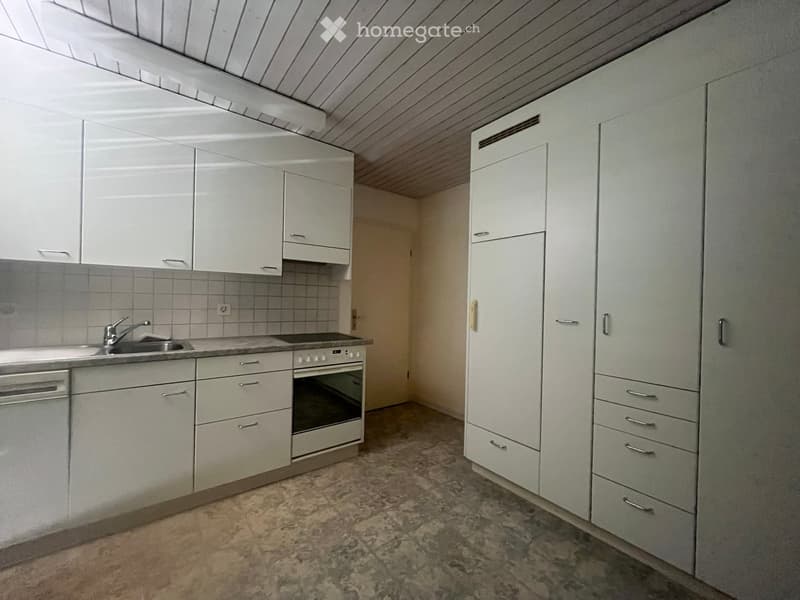 Modern kitchen with white cabinets, stainless steel sink, oven, and dishwasher. The space features a tiled backsplash and a marble floor.