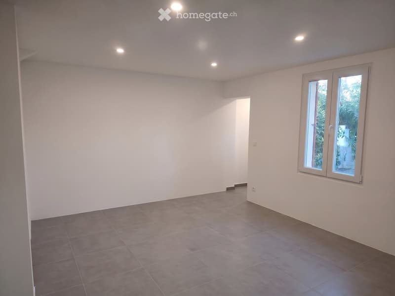 Empty room with white walls, tiled floor, and a large window with a view of greenery. No furniture or equipment is present.
