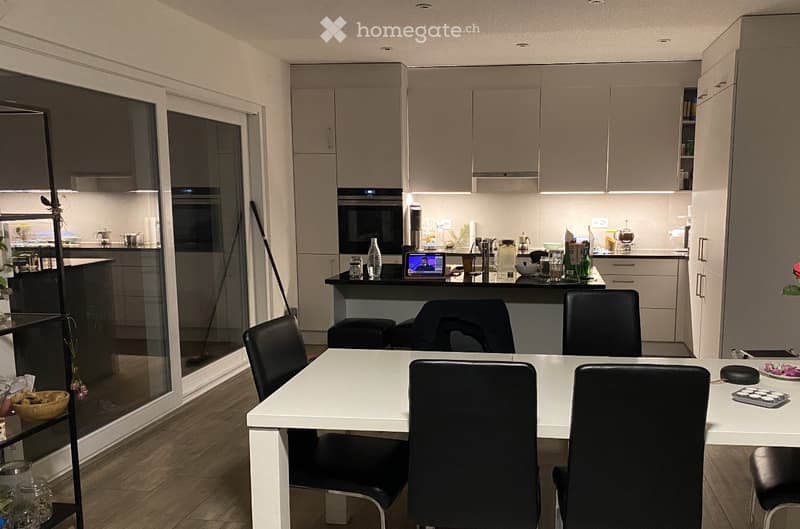 white cabinets, white countertops, modern kitchen appliances, large dining table, black chairs
