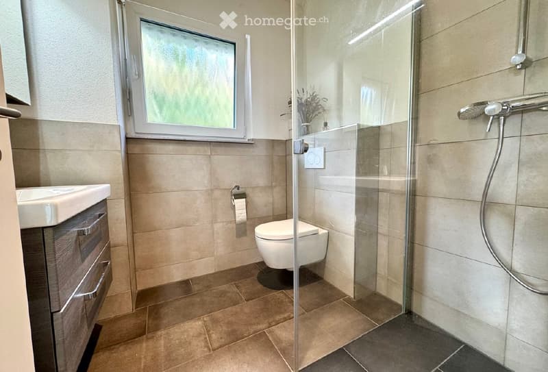 modern bathroom with a toilet, shower, sink, and a window