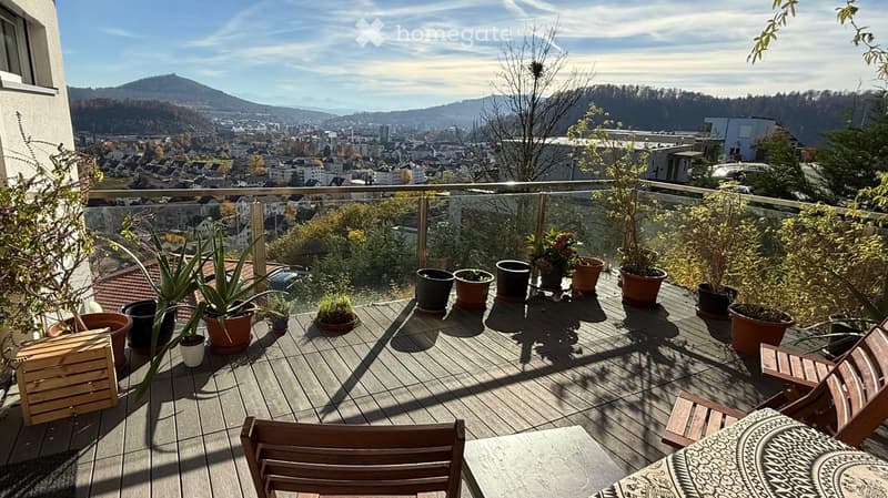Balcony/Terrace with wooden chairs, table, several potted plants, railing, city view in the background