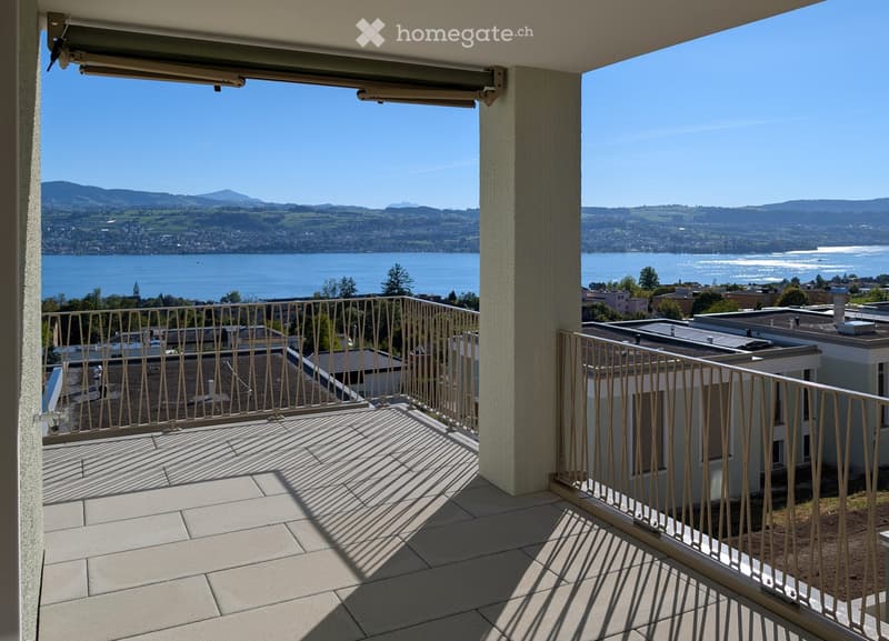 Balcony with tiled floor, metal railing, and scenic view of a lake and mountains.