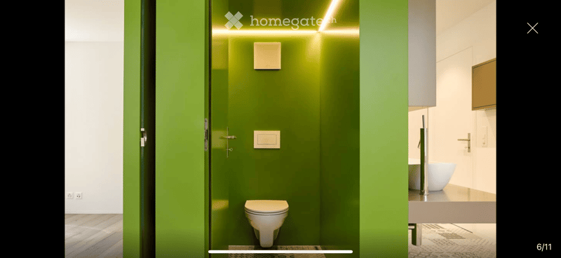 Modern bathroom with green accent wall, white toilet, white sink, and sleek faucet.