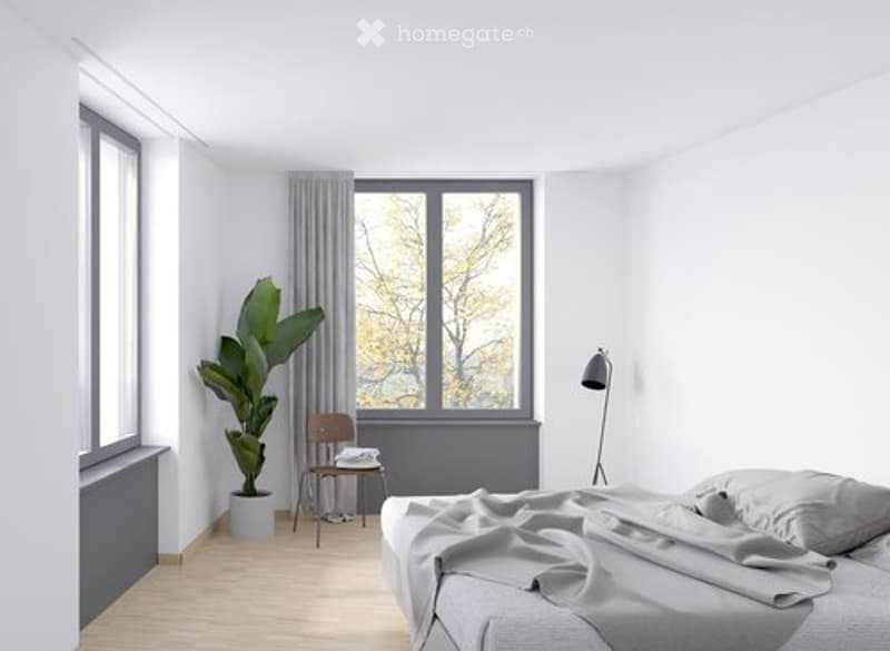 Modern, minimalist bedroom with a large window, grey bedding, a wooden chair, a small table, a floor lamp, and a leafy plant in a pot.