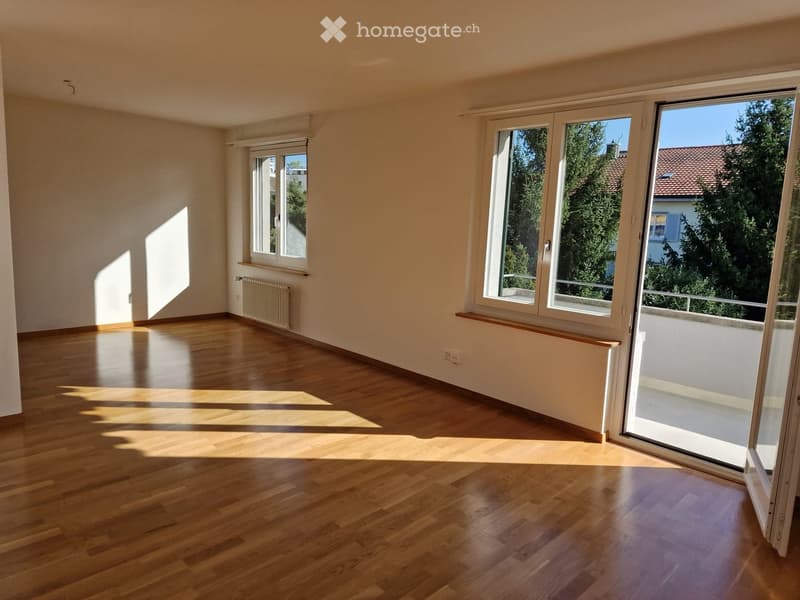 Empty room with wooden flooring, large windows, and natural light. No furniture or equipment present.