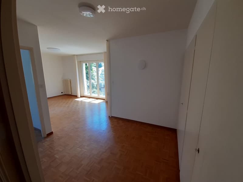 Empty room with wooden flooring, white walls, and large windows allowing natural light. No furniture or equipment is present.