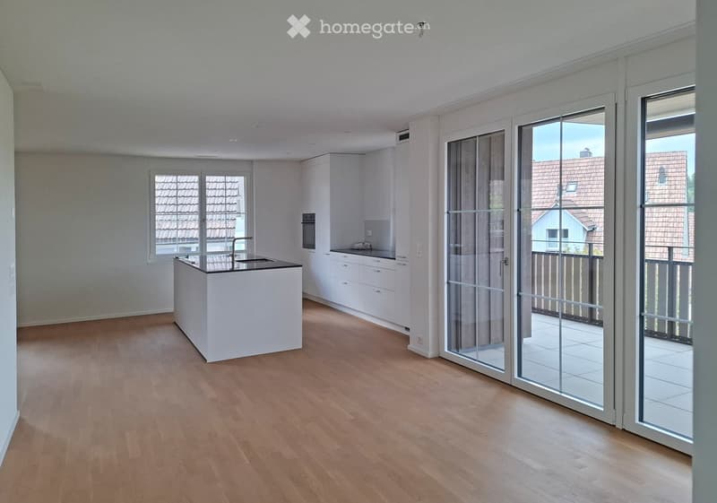 Modern kitchen with white cabinets, a central island, and large sliding glass doors leading to a balcony.