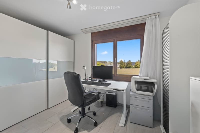 Modern office space with a white desk, black office chair, computer, printer, and a large window with a scenic view.
