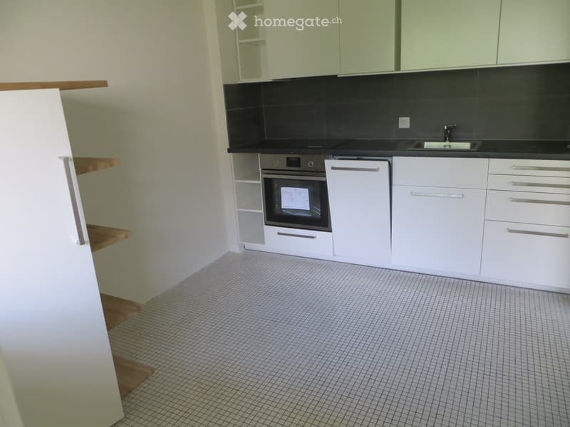 Modern kitchen with white cabinets, a built-in oven, and a sink, featuring a tiled floor and a black backsplash.