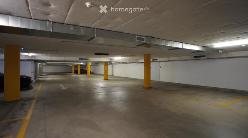 Empty parking lot with yellow lines, yellow pillars, white walls, and ceiling lights