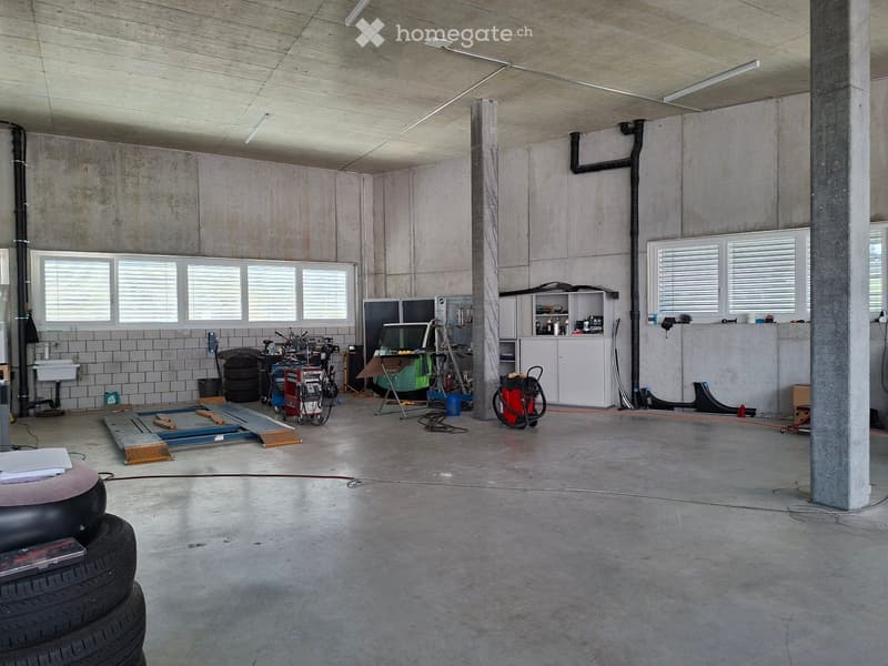 Garage with concrete walls and floor, equipped with a workbench, bicycle, cabinet, sink, and various tools.