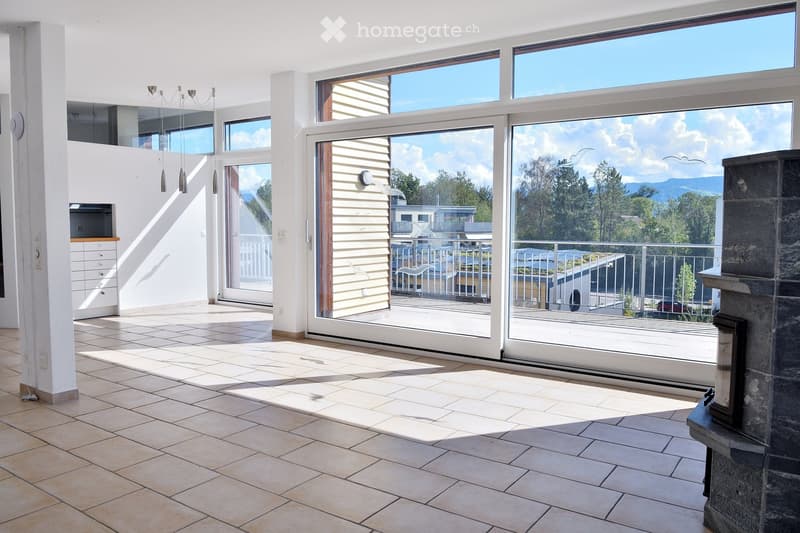 Bright, open living space with large glass doors leading to a balcony, tiled floor, fireplace, and built-in cabinetry.