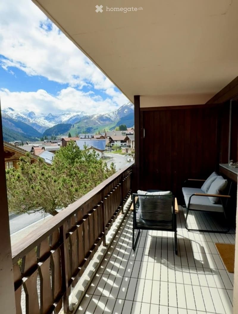 wooden railings, wooden floor, white tiled floor, two lounge chairs with cushions, view of mountains