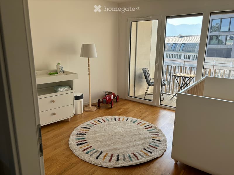 Child's room with wooden floor, round rug, floor lamp, toy car, and balcony with outdoor furniture and scenic view.