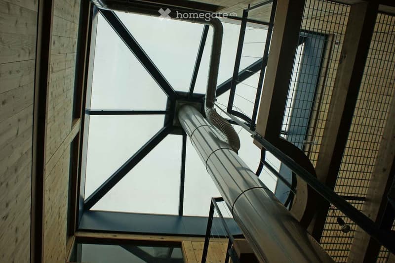 Modern interior view of a corridor with wooden walls, large glass window, and metal pipes.