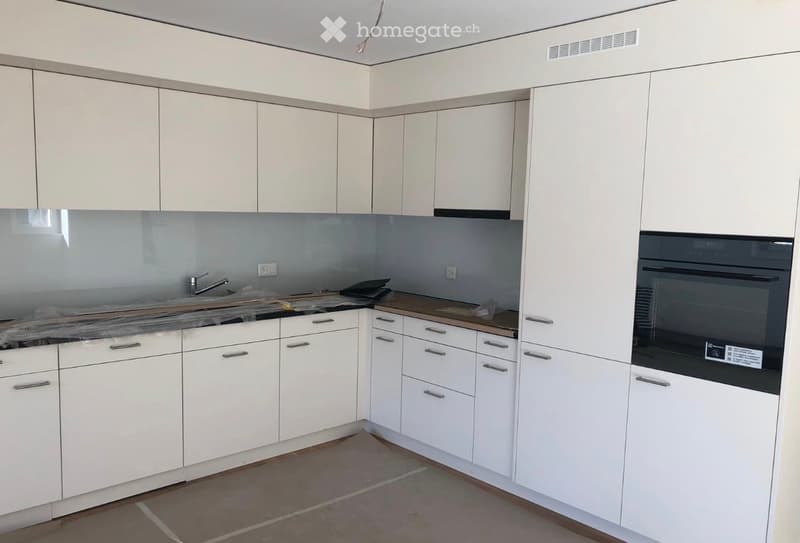 Modern kitchen with white cabinets, stainless steel appliances, and a sleek countertop.