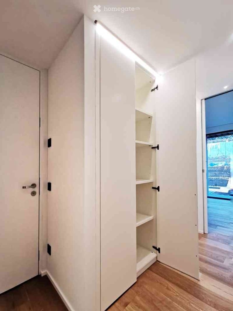 Empty room with white walls, wooden flooring, and a built-in closet with shelves. No furniture or personal items are present.