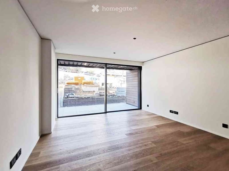 Empty room with wooden flooring, white walls, and large sliding glass doors leading to an outdoor area.