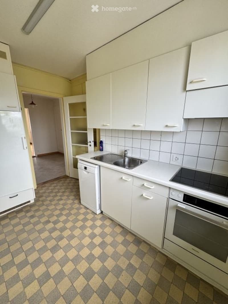 Modern kitchen with white cabinets, stainless steel appliances, and a checkered tile floor.