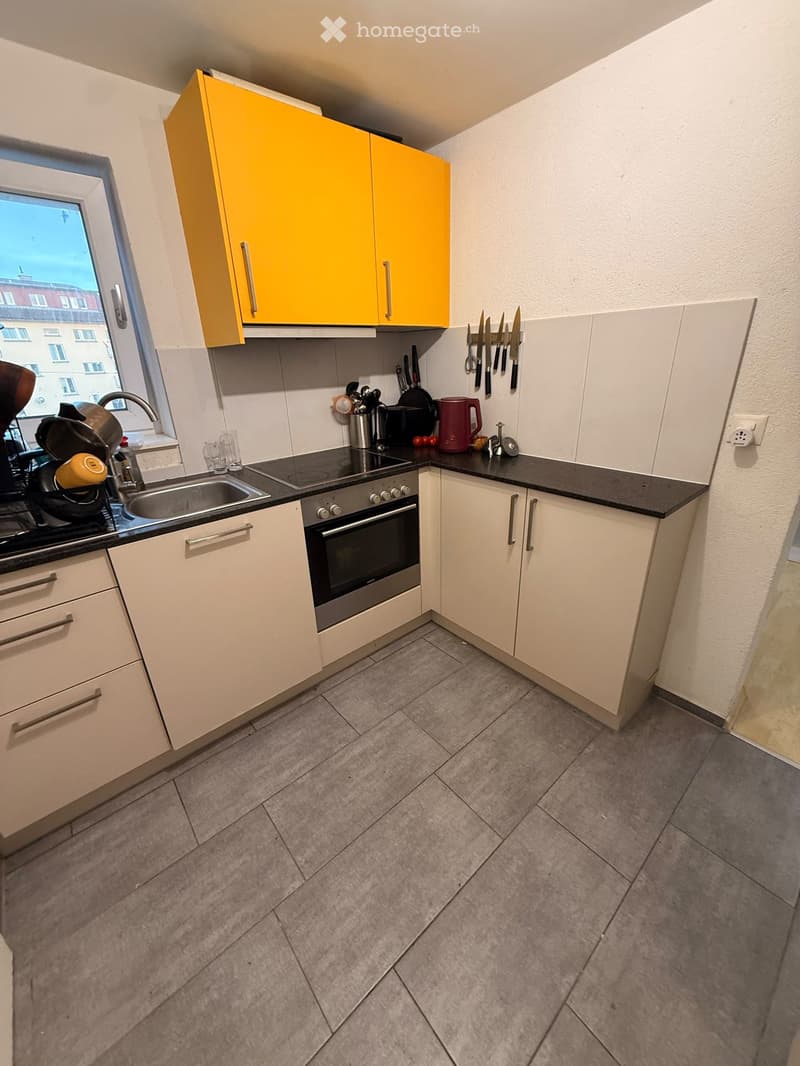 Modern kitchen with white and yellow cabinets, stainless steel appliances, and a black countertop.