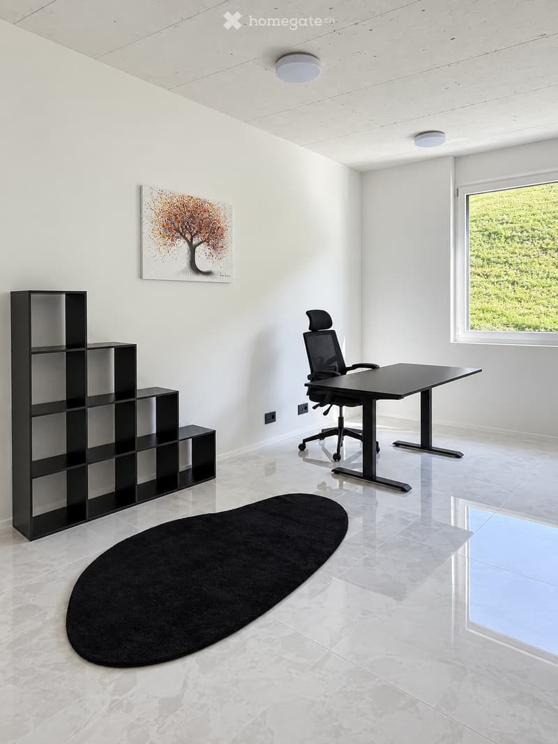 Modern office space with a black desk, ergonomic chair, black shelving unit, and a round black rug on a polished marble floor.