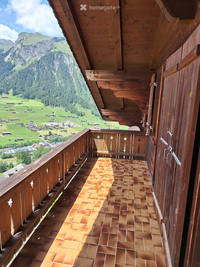 Balcony with wooden railings, tiled floor, and scenic mountain view.