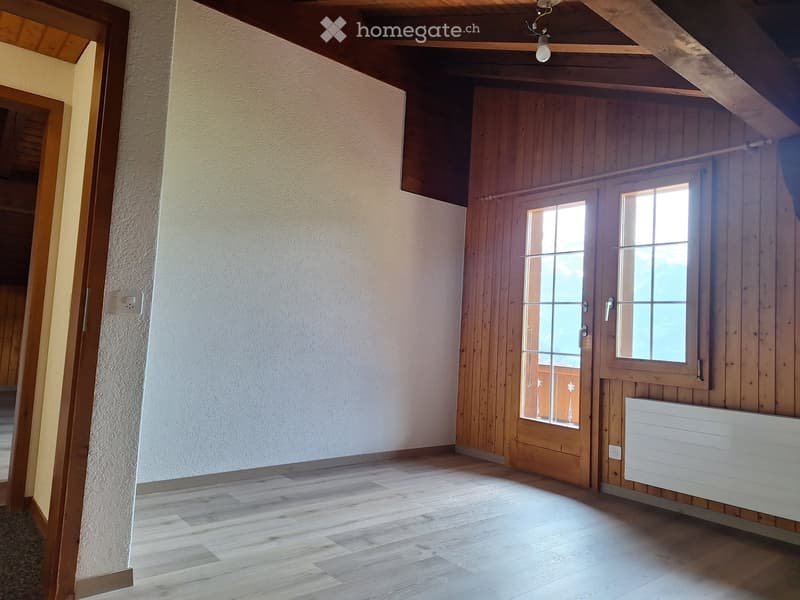 Empty room with wooden flooring, white walls, and a wooden door with glass panels leading to a balcony.