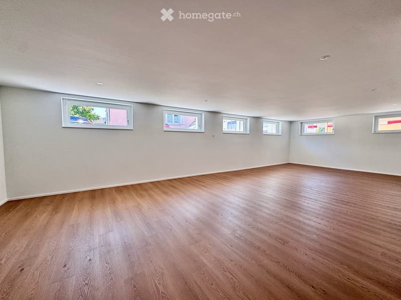 Empty room with wooden flooring and multiple windows, no furniture or equipment present.