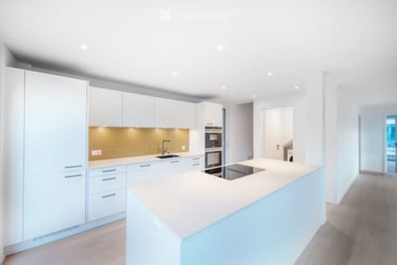 Modern, minimalist kitchen with white cabinets, a central island, and stainless steel appliances.