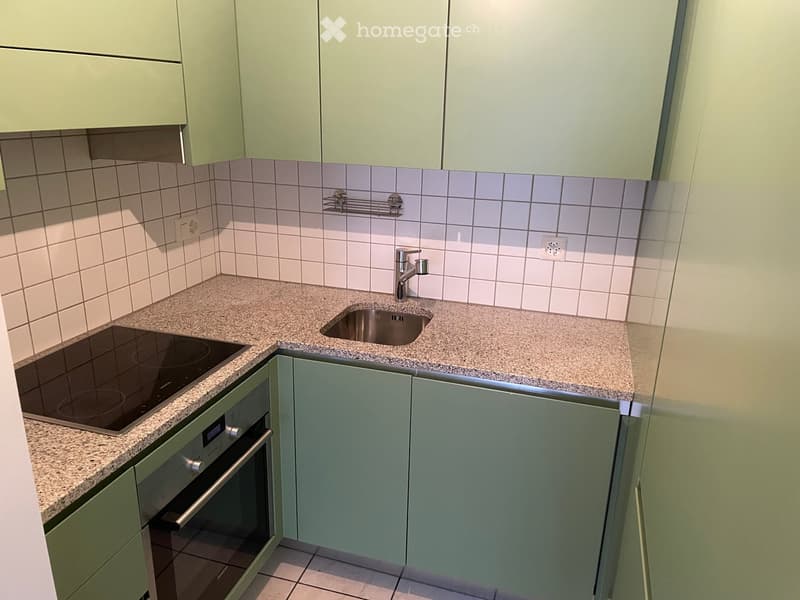 kitchen with green cabinets, granite countertop, induction stove, stainless steel sink, oven, power outlets, tiled walls