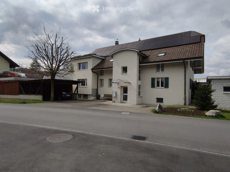 Two-story house with a garage, solar panels on the roof, and a driveway.
