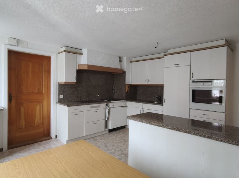Modern kitchen with white cabinets, granite countertops, and stainless steel appliances including an oven and dishwasher.